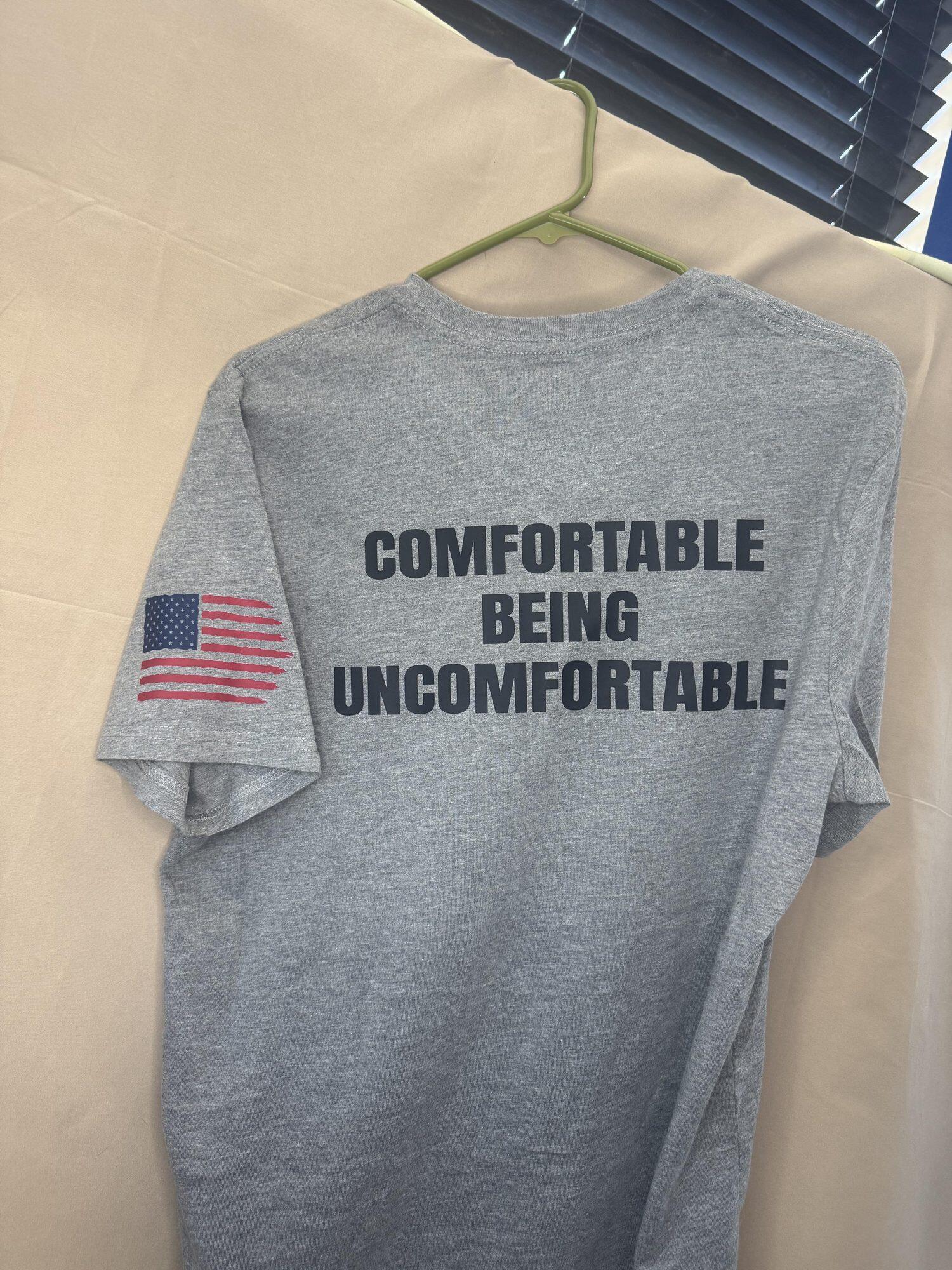 Heather grey t-shirt reading Comfortable Being Uncomfortable with a flag on the sleeve