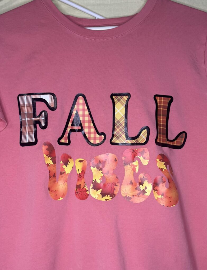 Dusty rose t-shirt with Fall vibes printed in plaid and maple-leaf letters